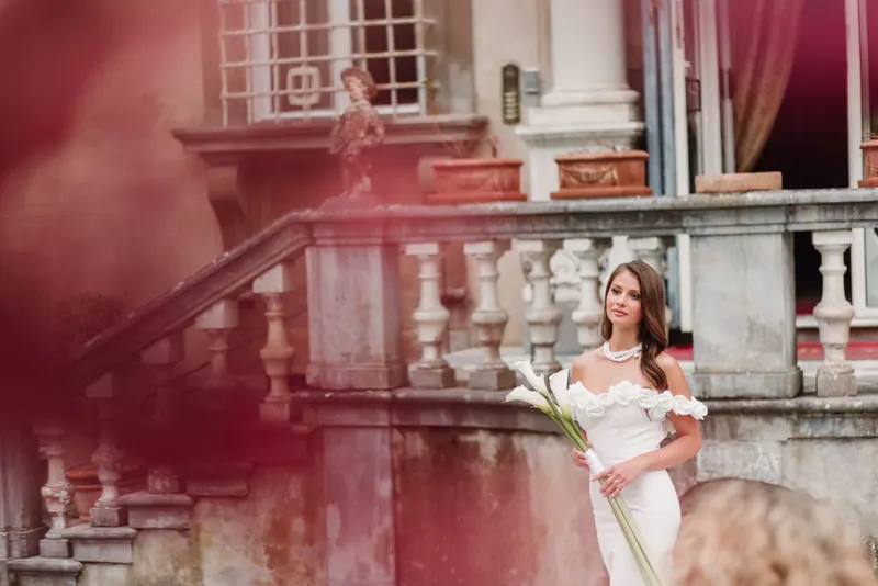 De bruid met calla's op de trappen, door rode bloemen gefotografeerd