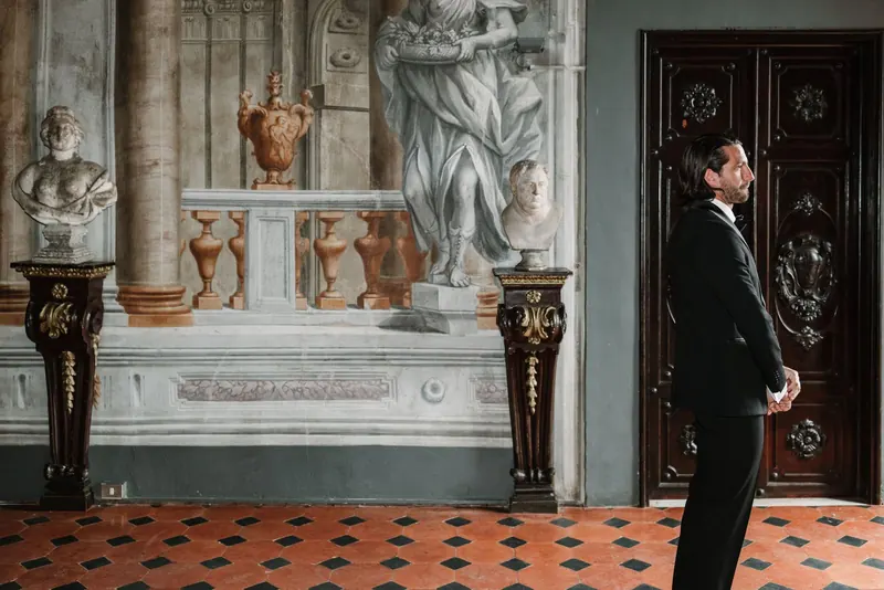 De bruidegom wacht met de rug naar de zaal op de first look