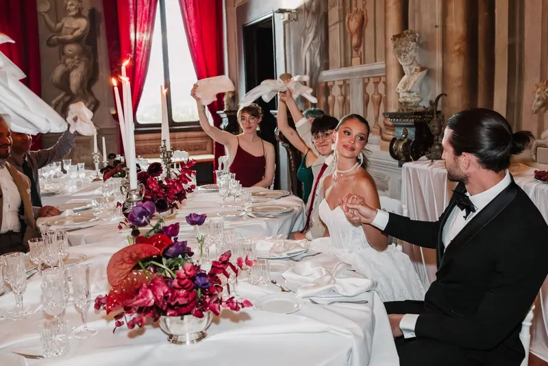 Het bruidspaar aan tafel tussen de bloemen en kaarsen