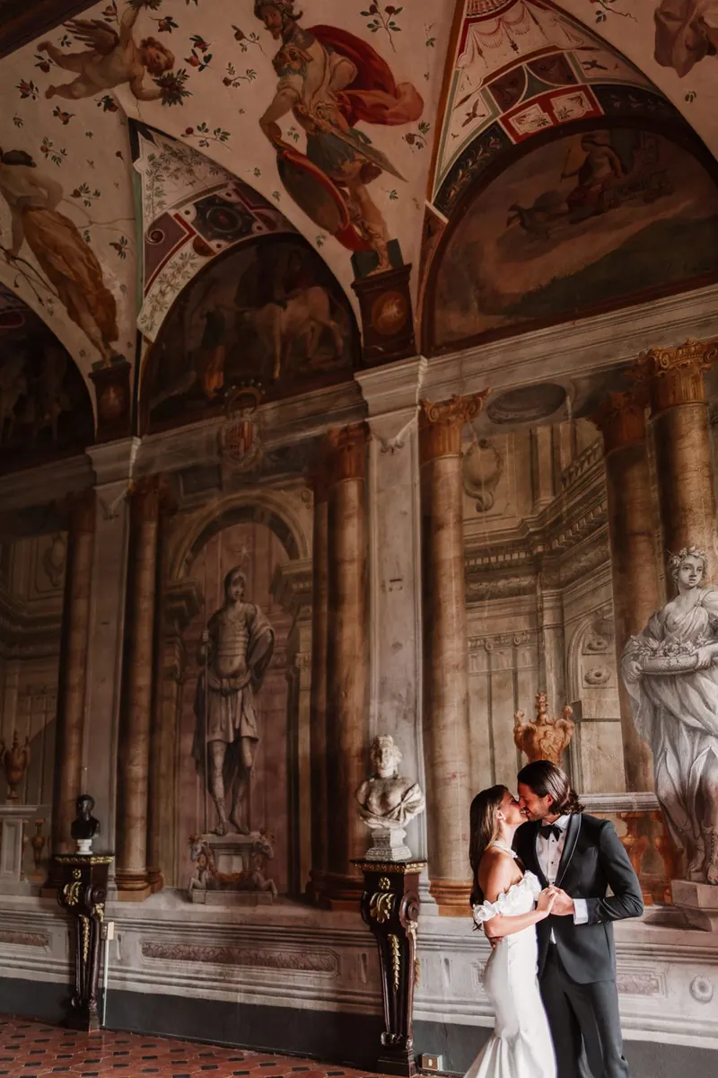 Het bruidspaar klein in de grote zaal vol fresco's en beelden