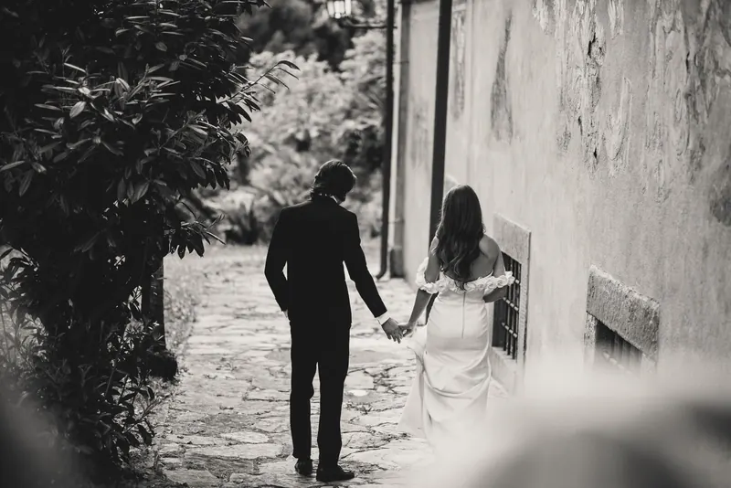 Het bruidspaar wandelt hand in hand door de tuin, monochrome foto