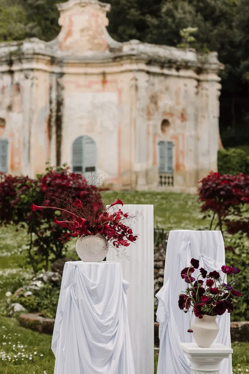 Ceremoniedecor met witte zuilen en rode bloemen voor het tuinpaviljoen