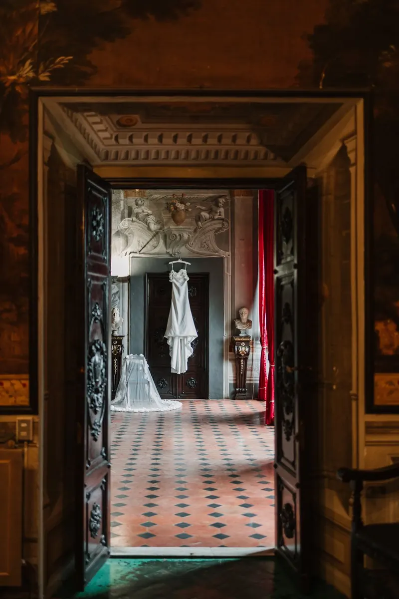 Doorkijk door de deuren van de villa naar de trouwjurk