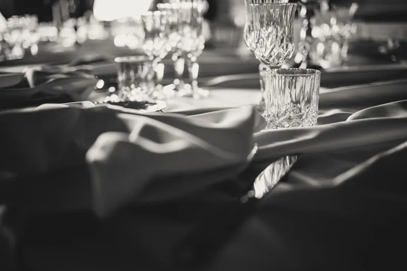 Kristallen glazen op de gedekte tafel, monochrome foto
