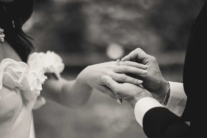 De ring wordt aan de vinger van de bruid geschoven, monochrome foto
