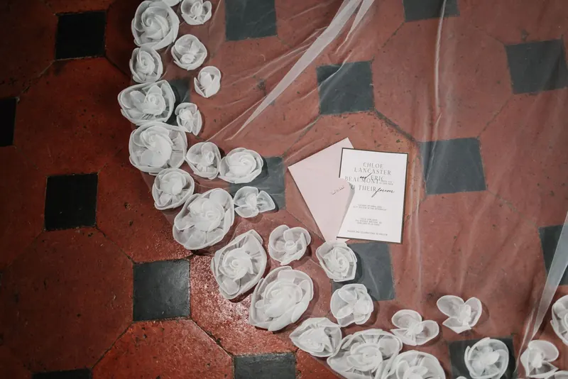 Sluier, zijden rozen en naamkaartje op de terracotta tegelvloer