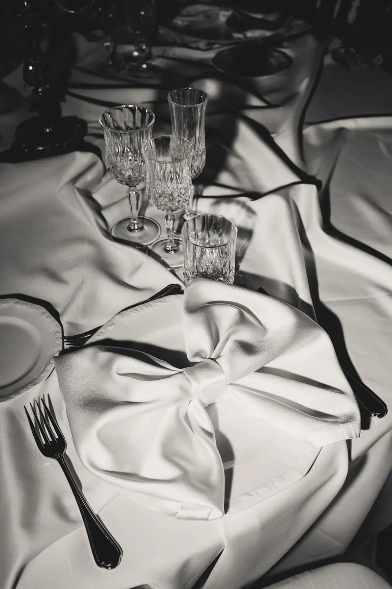 Glazen en servet op het witte tafellinnen, monochrome foto