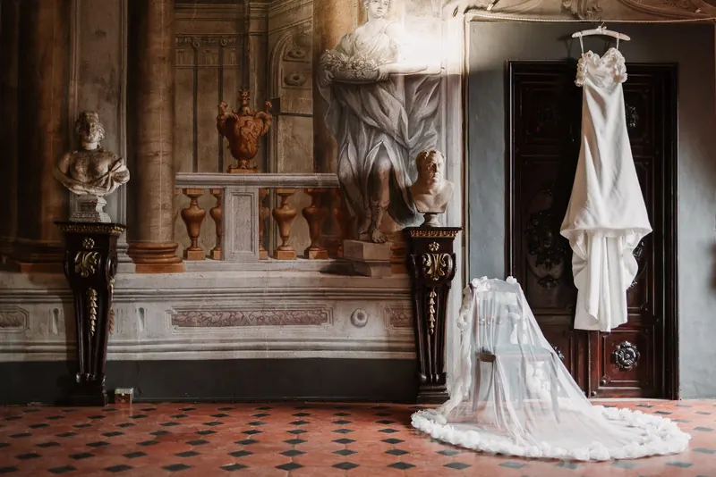 De trouwjurk hangt klaar in een salon vol fresco's en marmeren bustes