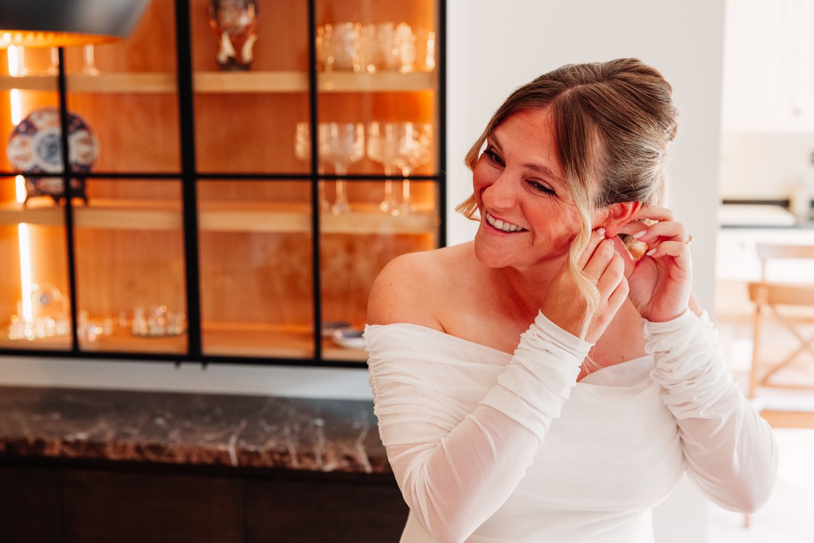Julie lacht terwijl ze haar oorbellen indoet op de ochtend van haar bruiloft
