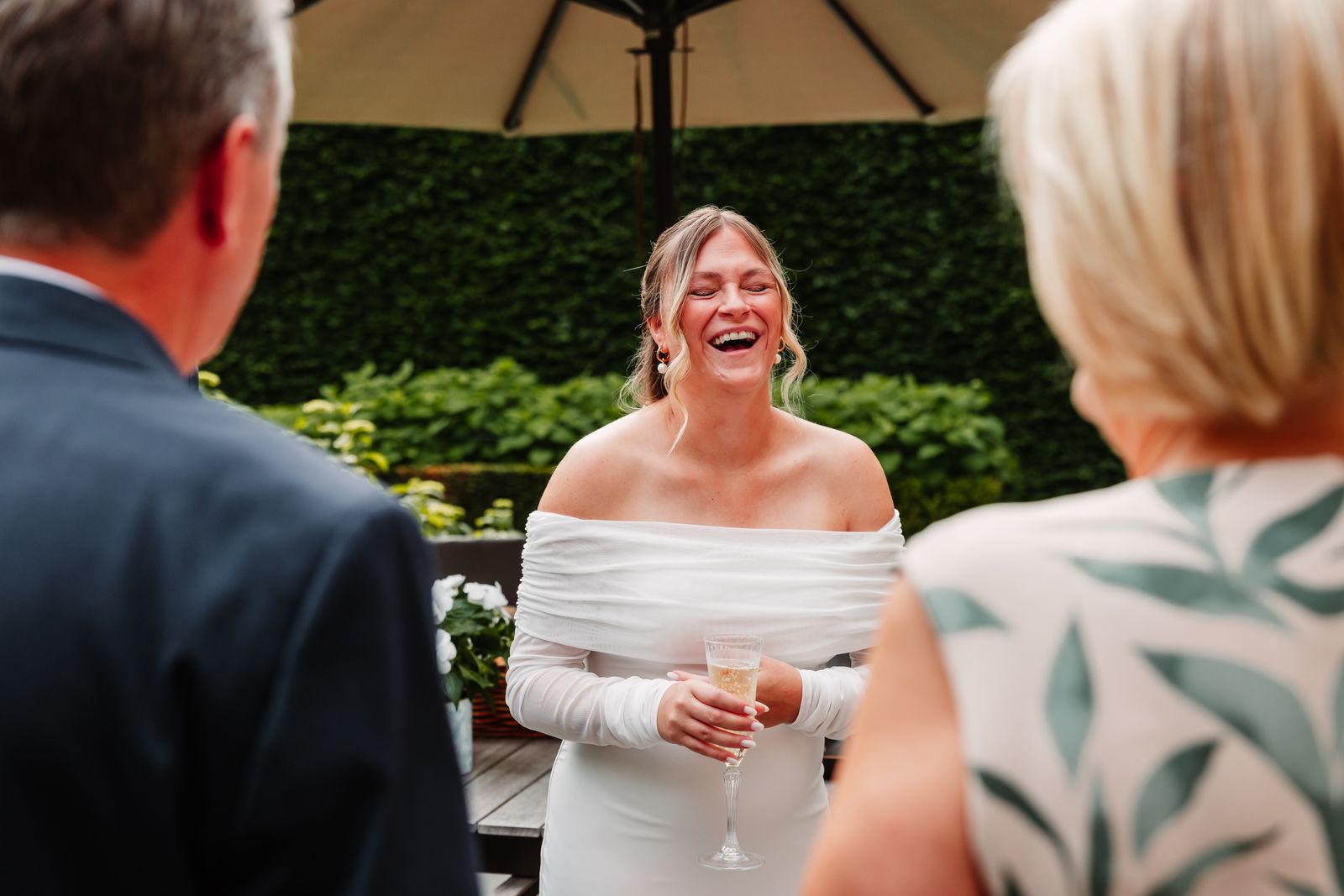 Julie lacht tussen familie bij de champagne op het terras