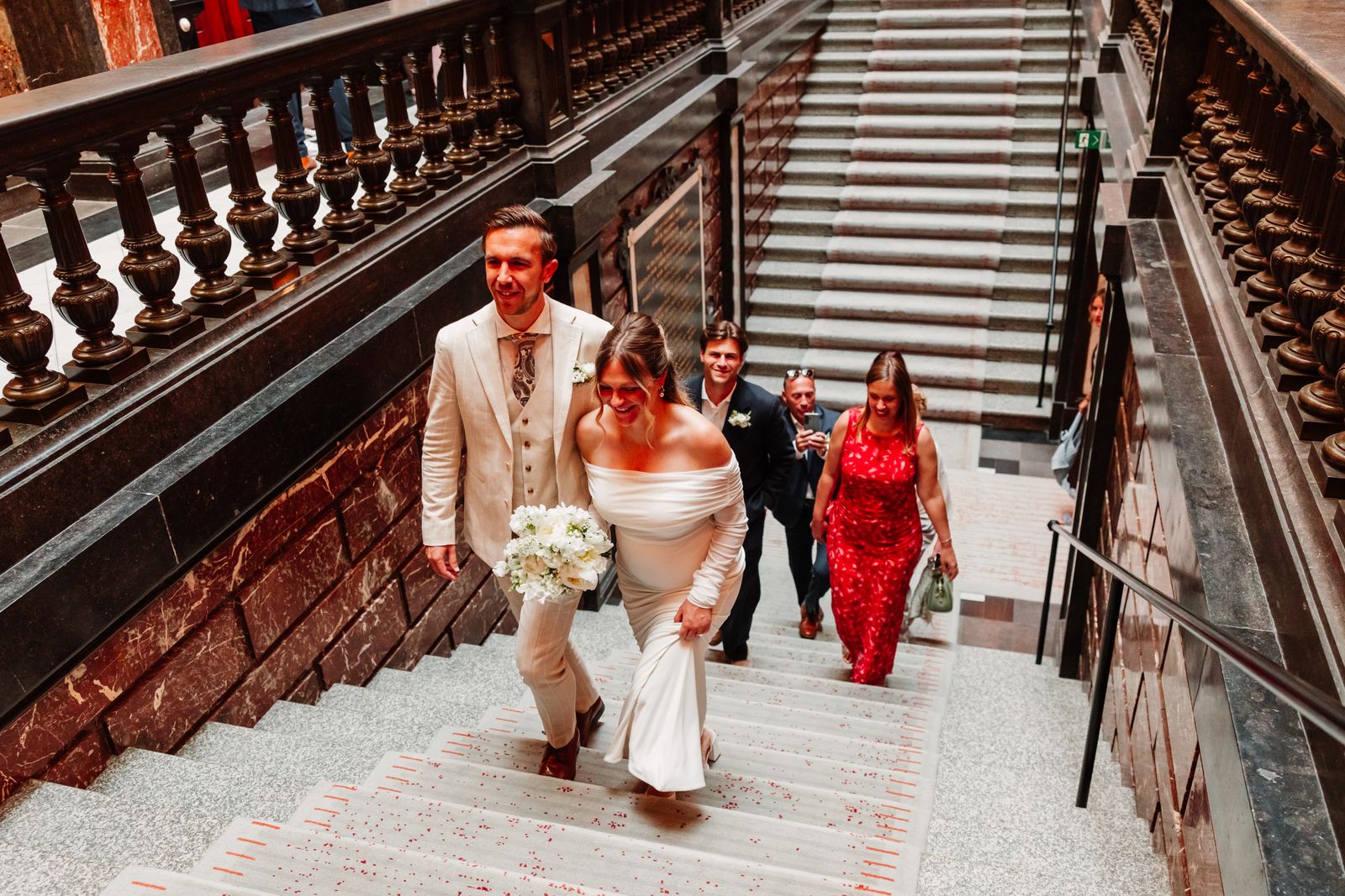 Het bruidspaar loopt de marmeren trap op in het stadhuis van Antwerpen